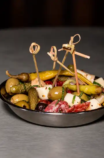 Aperitivo con salami, queso, aceitunas, pepinillos y chiles, servido con palillos de bambú